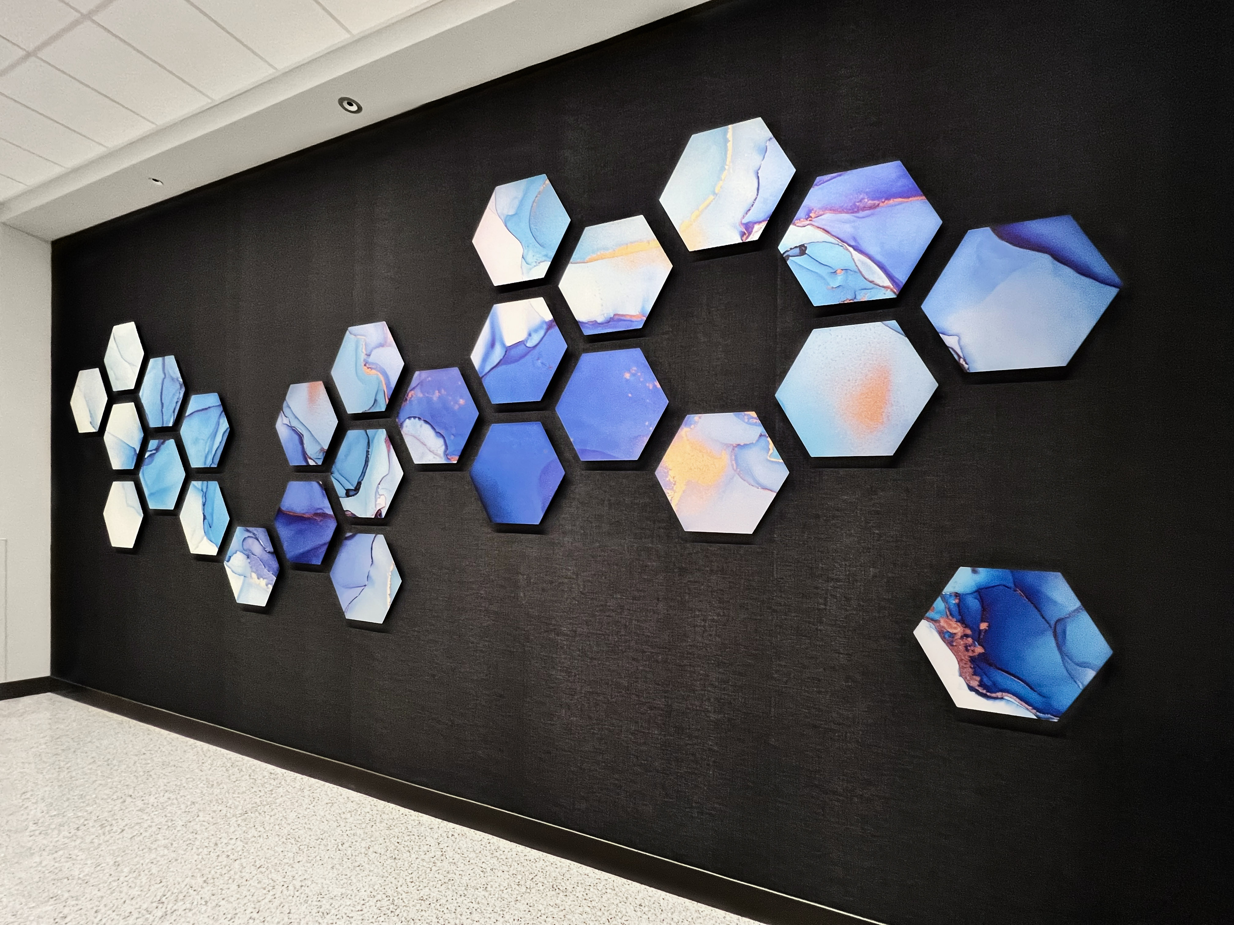 Large black wall with hexagon artwork installed in a pattern.